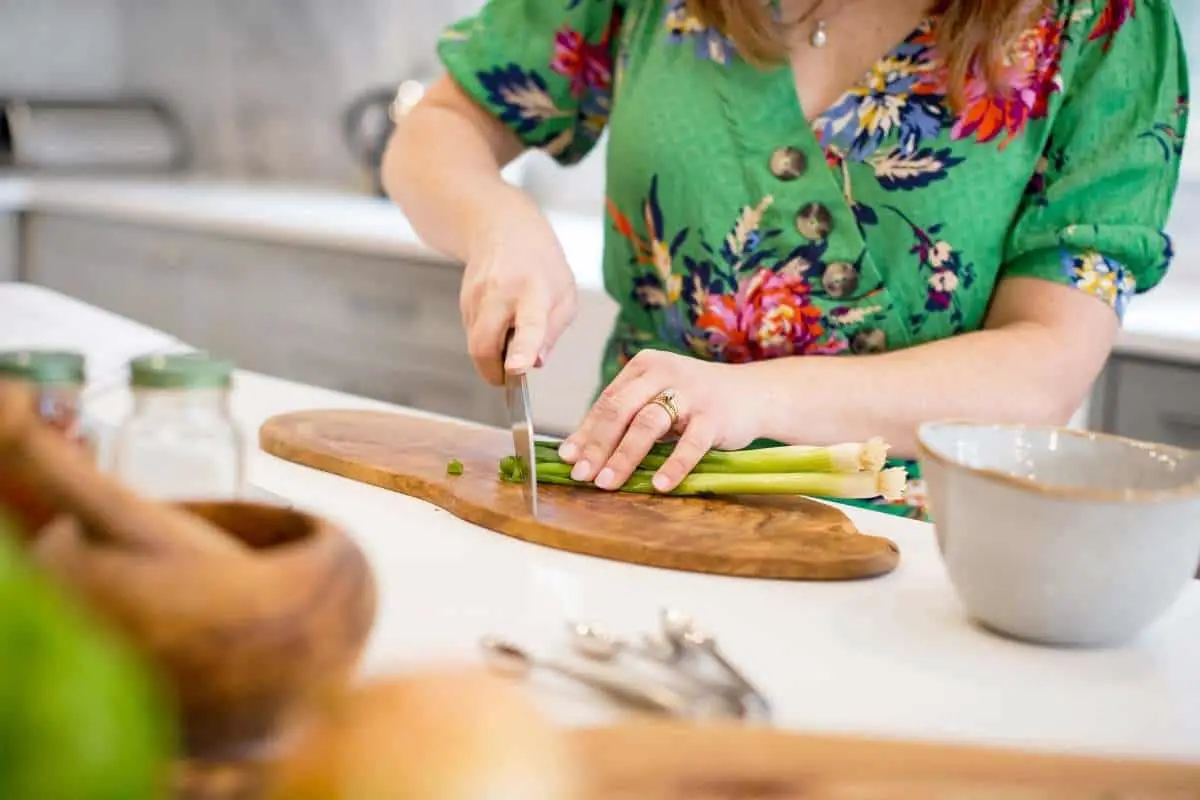 woman in home kitchen chopping green onion