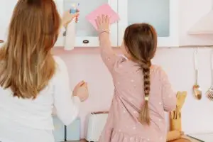 girl and mom wiping cabinet